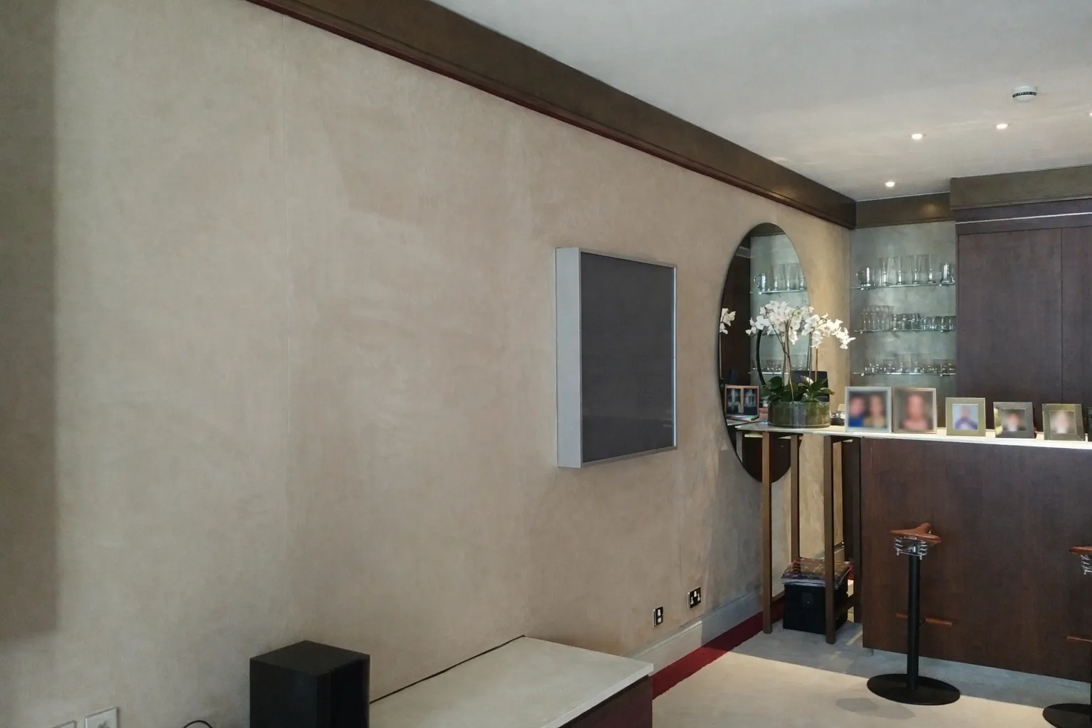 Modern interior with a textured wall, round mirror, and decorative plants