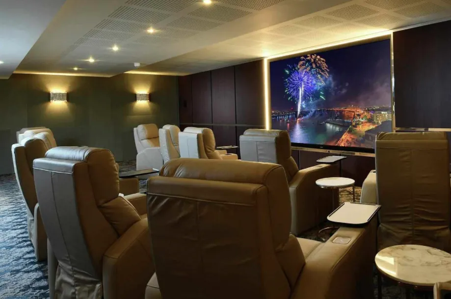 Luxury theater seating with a large screen showing fireworks over a cityscape