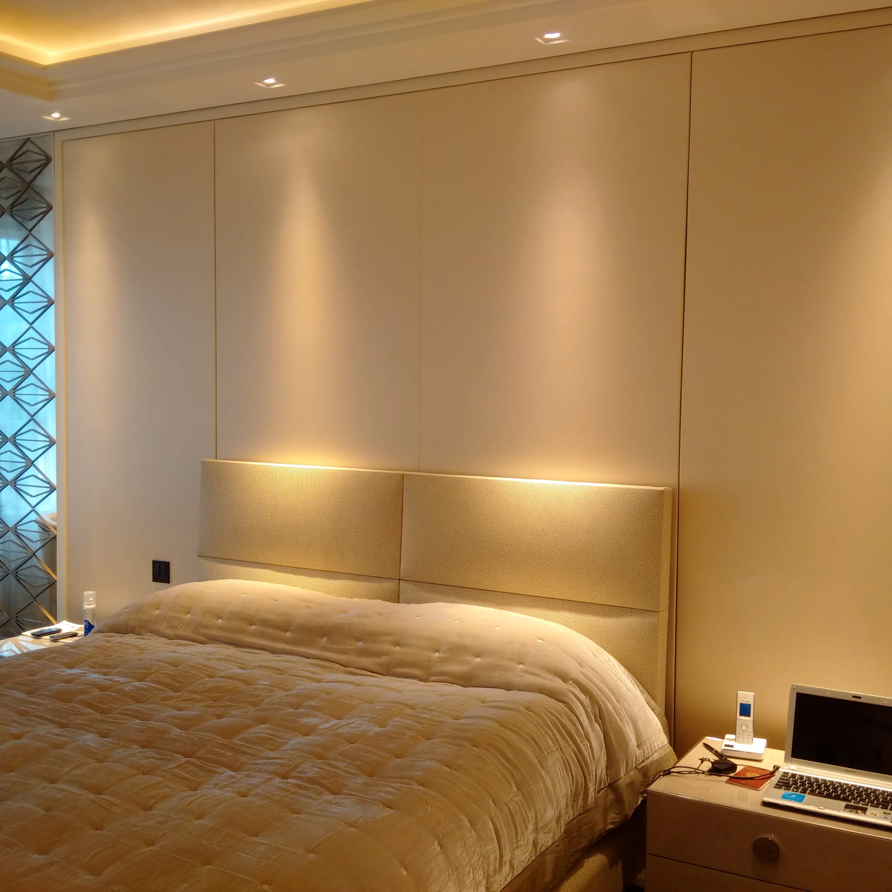 Modern bedroom with soft ambient lighting and a tailored fabric wall finish