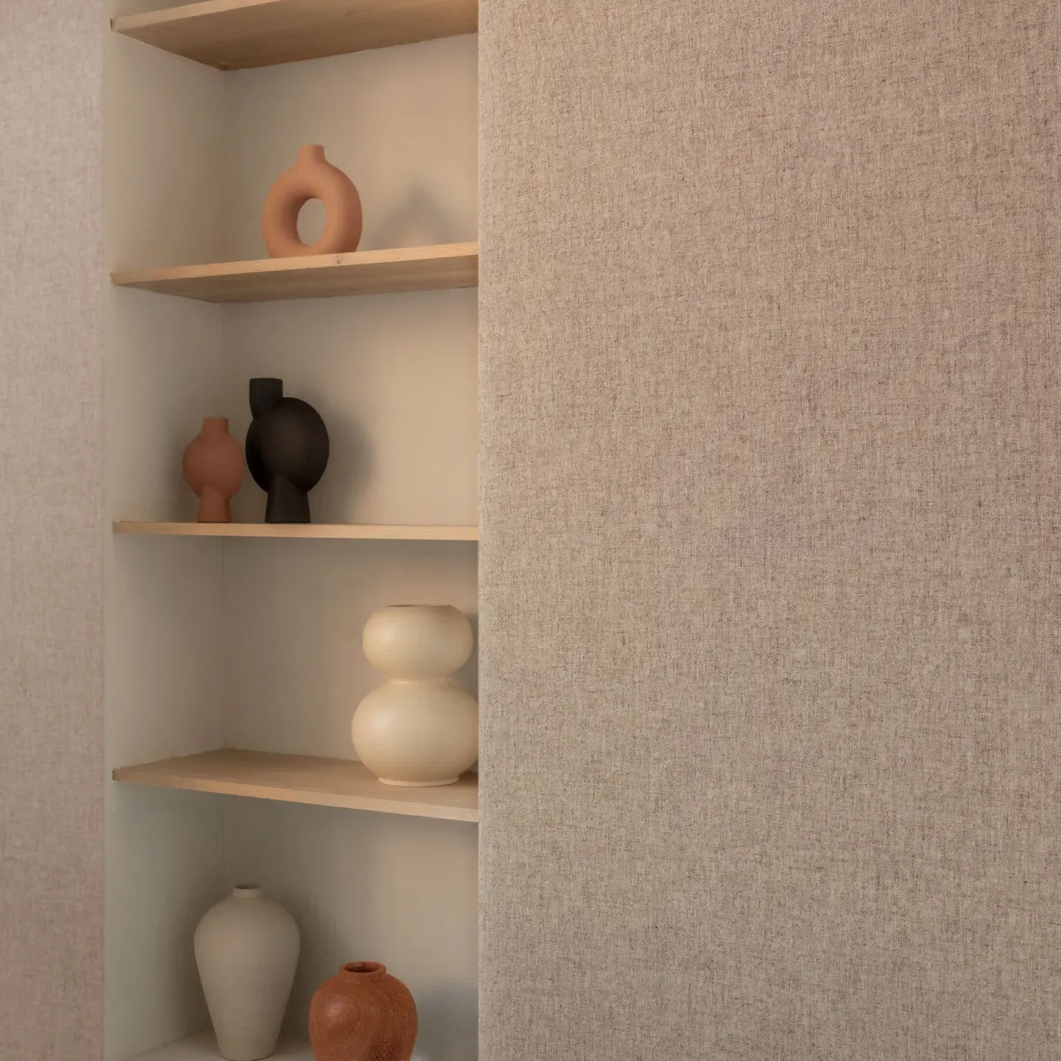 Decorative ceramics displayed on wooden shelves in a minimalist residential setting